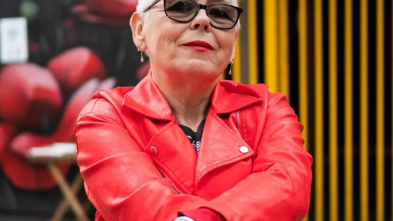 A woman in a red leather jacket against a graffiti background