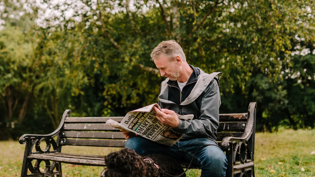 A man sitting on a bench reading a newspaper