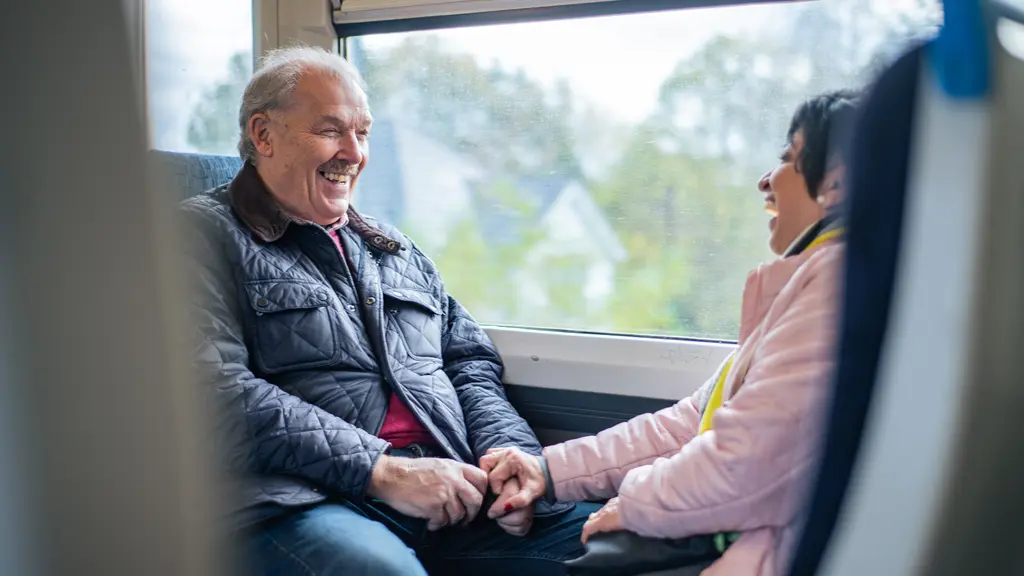 An older couple holding hands on a train