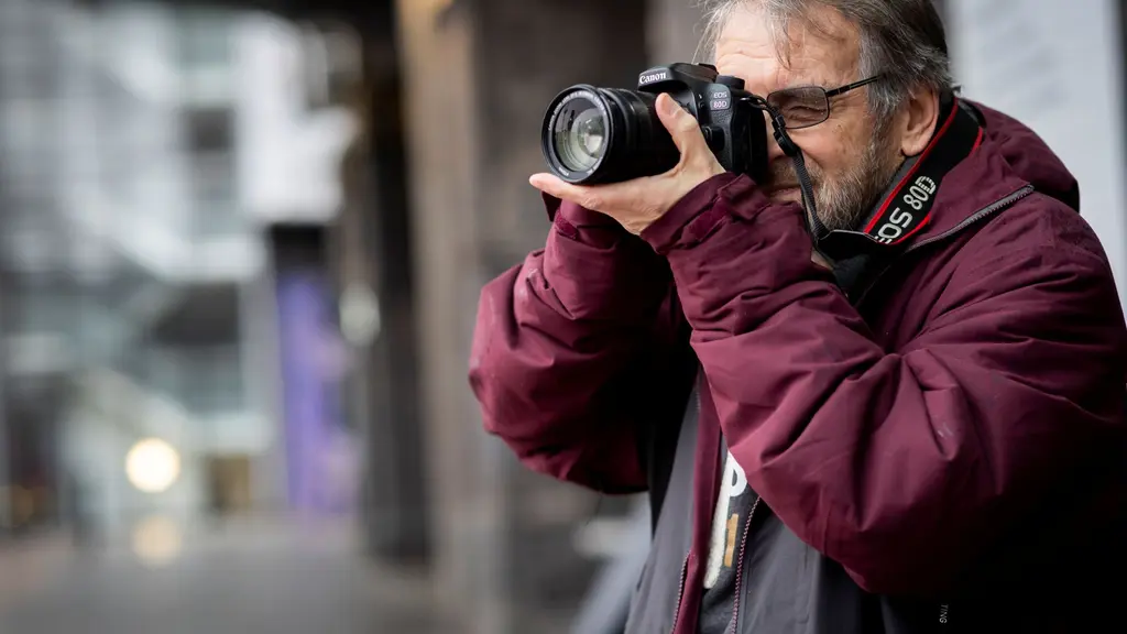 A man outside taking a picture on a digital camera