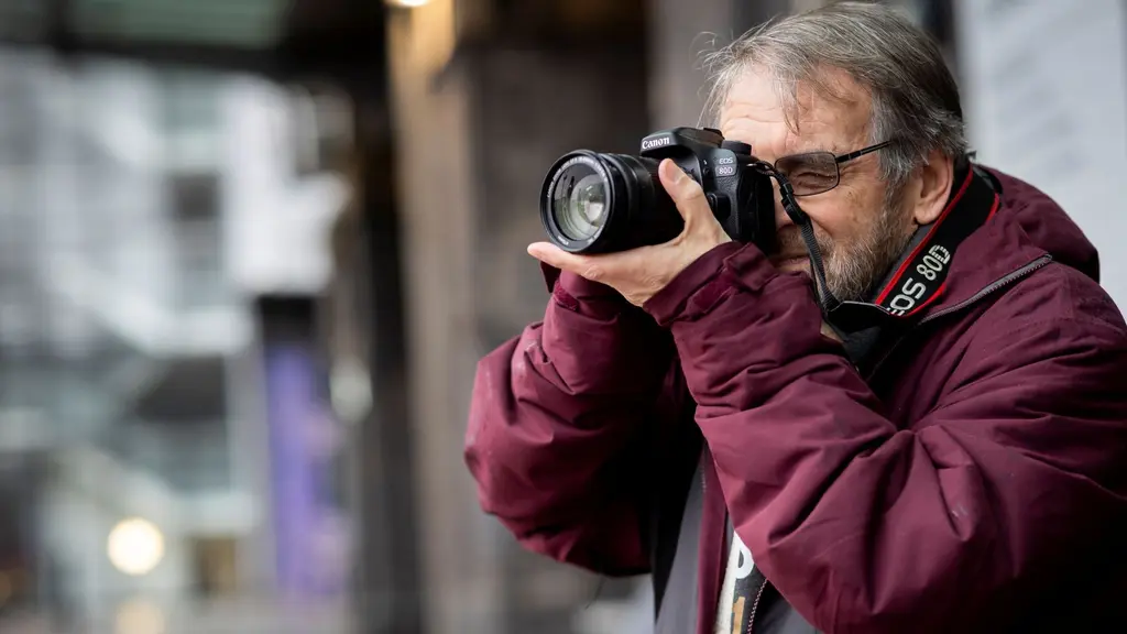 A man outside taking a picture on a digital camera