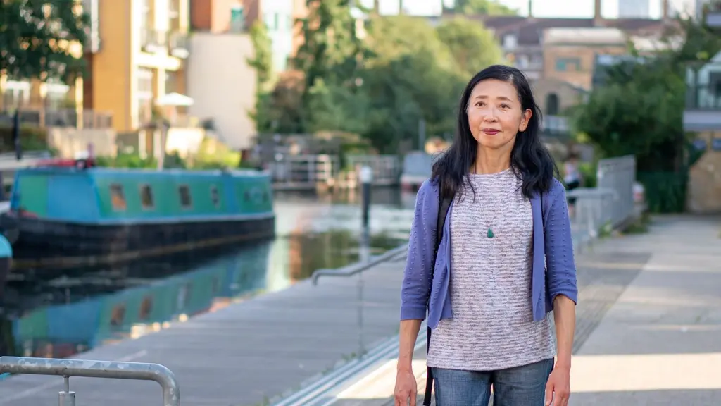 An older woman walking outside with a canal behind her