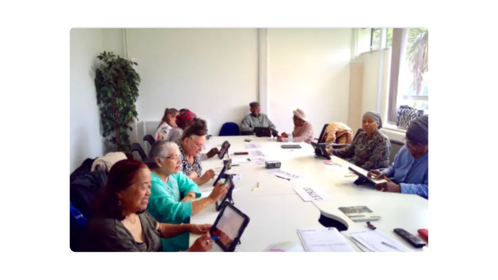 A group of people sit at a table on tablets to do digital drawings
