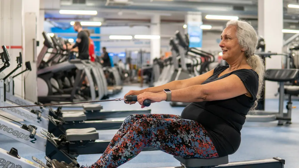 A woman using a rowing machine in a gym