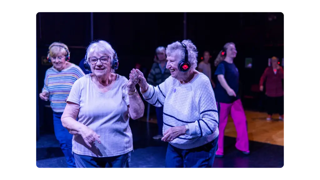 Two older women dance together at a silent disco