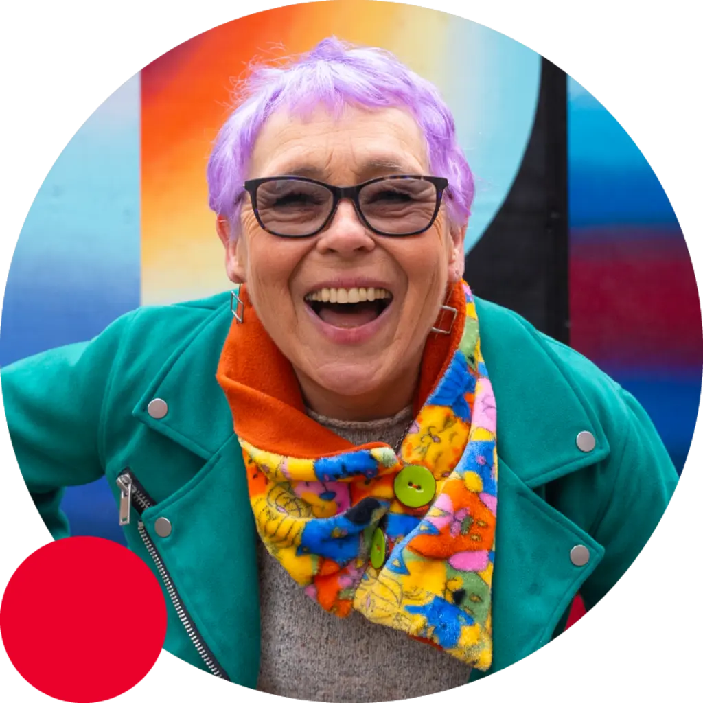 woman with purple hair and glasses smiling with joy
